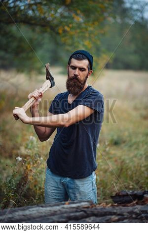 Serious Man With A Thick Beard And A Large Mustache In A Dark Sleeveless T-shirt And A Warm Hat With