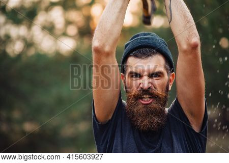 Stylish Brutal Bearded Man Lumberjack With A Long Beard And Mustache In A T-shirt And A Warm Hat Wit