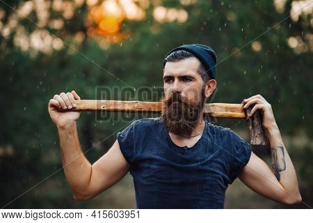 Stylish Brutal Bearded Man Lumberjack With A Long Beard And Mustache In A T-shirt And A Warm Hat Wit