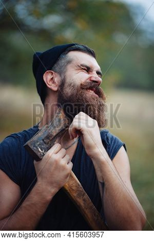 Stylish Brutal Bearded Man Lumberjack With A Long Beard And Mustache In A T-shirt And A Warm Hat Wit