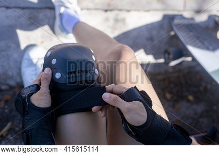 Top View Close Up Woman Surf Skate Board Putting On Knee Protector Pads On Her Arm And Wearing Wrist