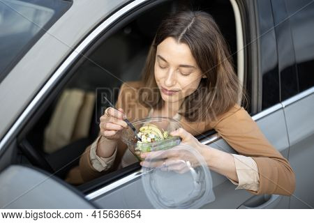 Beautiful Woman Eating Heathy Salad In The Car. Received A Food Order To Go. Have A Quickly Snack On