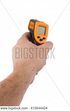 A Man Holds A Yellow-black Pyrometer. A Device For Non-contact Temperature Measurement. Studio Photo
