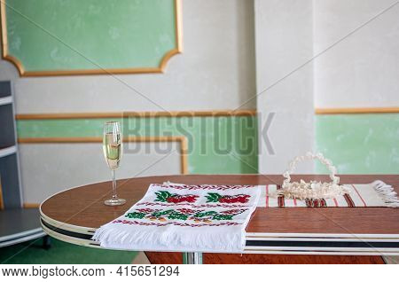 A Glass Of Champagne And An Embroidered Towel Stands On The Table