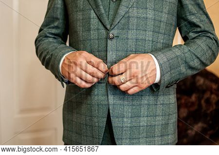 Groom Buckles The Button On His Jacket