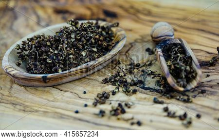 Dried Brown Andaliman Pepper On Olive Wood