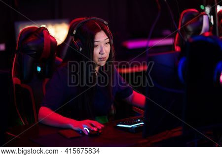 A Close-up Portrait Of A Gamer Girl Wearing Headphones In A Computer Club While Playing A Game