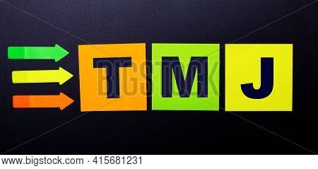 Bright Multi-colored Paper Stickers On A Black Background With The Text Tmj
