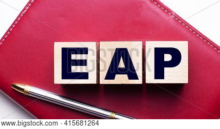 Eap Employee Assistance Program Made Up Of Wooden Cubes That Stand On A Burgundy Notebook Near The P