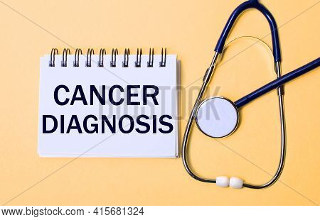 On A Beige Background, A Stethoscope And A White Notepad With The Inscription Cancer Diagnosis. Medi