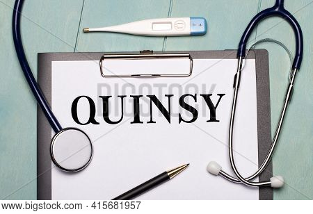 On A Light Blue Wooden Background, There Is A Paper Labeled Quinsy, A Stethoscope, An Electronic The