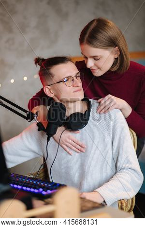 Beautiful Blod Hair Woman Hug His Husband During The Work On Computer. Happy Couple Working At Home.