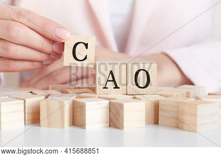 The Word Cao On A Wooden Toy Blocks With Womans Hands, Pink Background. Business Concept. Cao Short 