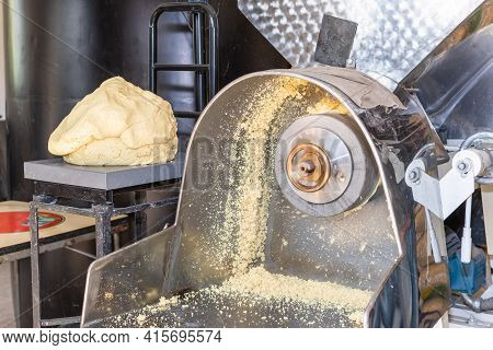 Front View Of A Nixtamal Mill While A Man Takes Out The Dough That Is Being Produced