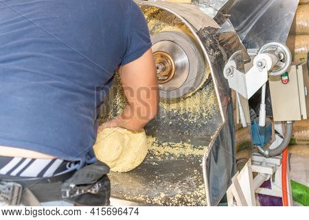 Front View Of A Nixtamal Mill While A Man Takes Out The Dough That Is Being Produced