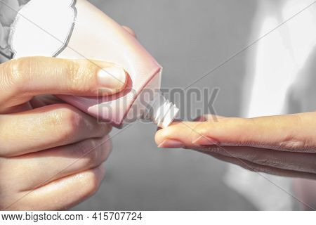 Girl Applying Cream On Finger, Close Up. Woman Holding Cream Tube And Applying Moisturizer Cream On
