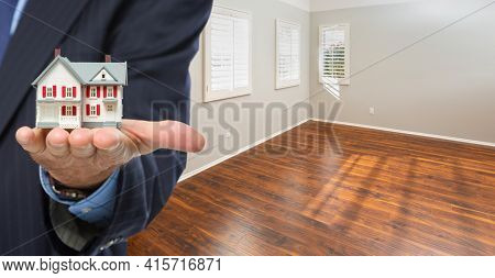 Real Estate Agent Holding Model Home Iside Empty Room of New House.