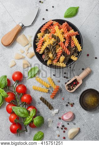 Fresh Raw Tricolore Fusilli Pasta In Black Bowl With Cherry Tomatoes And Basil, Garlic And Oil With 