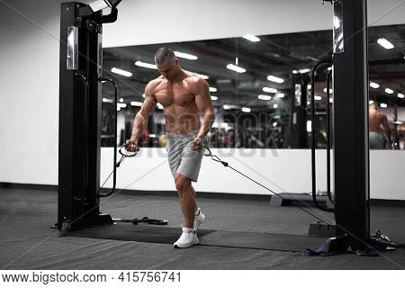 Muscular Athletic Bodybuilder Standing Training Chest And Shoulders Muscles On Fitness Equipment Wir