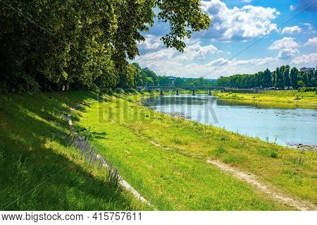 Embankment Of The River Uzh. Wonderful Urban Scenery In Summer. View From Beneath The Shadow Of A Li