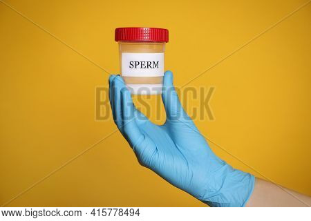 Scientist Holding Container With Sperm On Yellow Background, Closeup