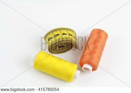 Skeins Of Colored Thread Orange, Yellow For Sewing And Twisted Yellow Measuring Tape. The Concept Of