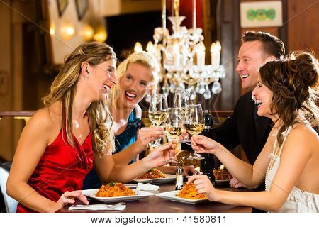 Buoni amici a cena o pranzo in un ristorante raffinato, tintinnio di bicchieri