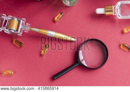 Magnifying Glass Against The Background Of Face Serums And Dermoroller