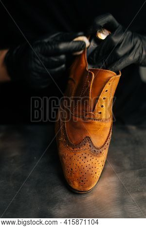 Close-up Of Shoemaker Wearing Black Latex Gloves Cleaning Old Light Brown Leather Shoes With Rag For