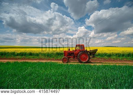 Red Tractor In A Field And Dramatic Clouds