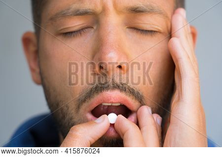 Man Suffering From Headache. Painkillers To Relieve Pain. Close Up Of Man Face Holding Temple And Ta