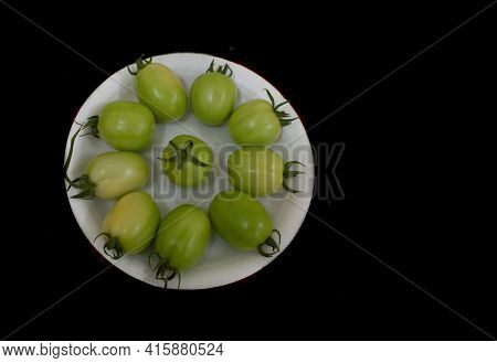 Collection Of Unripened Raw Green Tomatoes On A Plate Isolated On Black