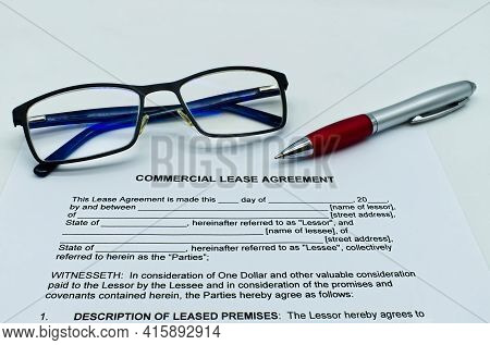 Model Of Commercial Lease Agreement On A White Table, With Glasses And Pen