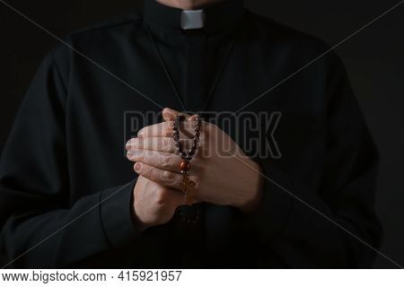 Priest With Beads Praying On Dark Background, Closeup