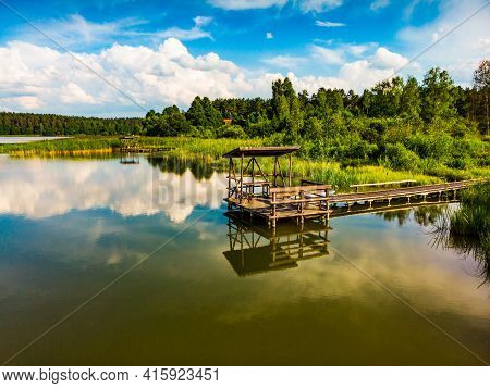 Green Summer Landscape In Europe. Wooden Jetty On Shore Of Lake Kierwik In Masuria Poland. Blue Sky 