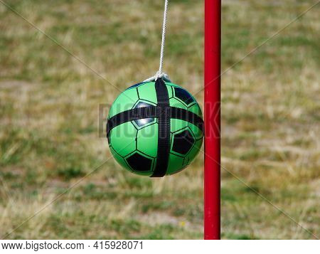 Tetherball Totem Ball Attached To A Red Metal Pole With Grass In The Background And Space For Graphi