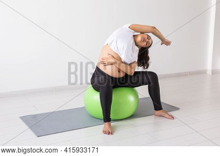 Young Flexible Pregnant Woman Doing Gymnastics On Rug On The Floor On White Background. The Concept 