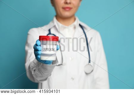 Doctor Holding Container With Sperm On Turquoise Background, Closeup. Space For Text