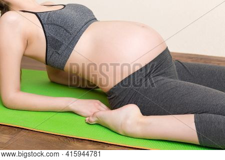 Beautiful Young Pregnant Woman Sitting On Mat In Yoga Pose At The Home. Pregnancy Yoga And Fitness C