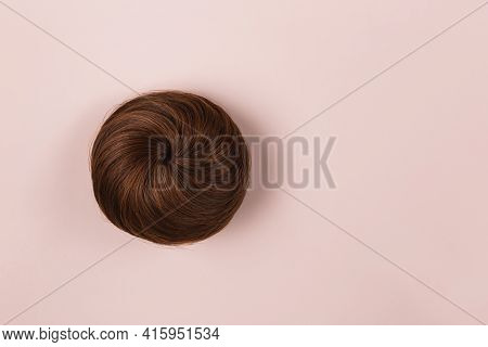 A Brown Hairpiece On The Pink Background. Flat-lay.