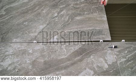 Construction Worker Tiler Is Tiling, Tiler Installing Ceramic Tiles On A Floor. Industrial Tiler Lay