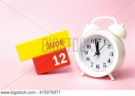 June 12nd. Day 12 Of Month, Calendar Date. White Alarm Clock On Pastel Pink Background. Summer Month