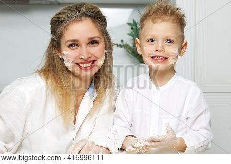 Happy Mom And Boy In White Kitchen Smeared Face With Flour