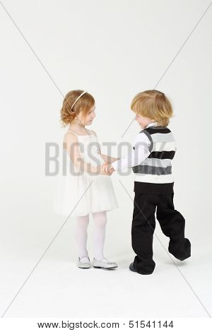 Little happy smiling girl and boy dance on white background.