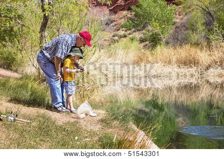 Grandpa fishing with his grandson at a beautiful lake