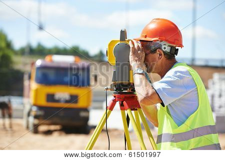 Portrait of builder worker with theodolite transit equipment at construction site outdoors during surveyor work