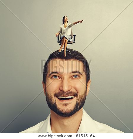 earnest woman pointing at something and sitting on the head of happy man