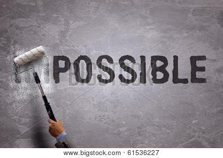 Changing the word impossible to possible by painting over and erasing part of the word with a paint roller on a concrete wall