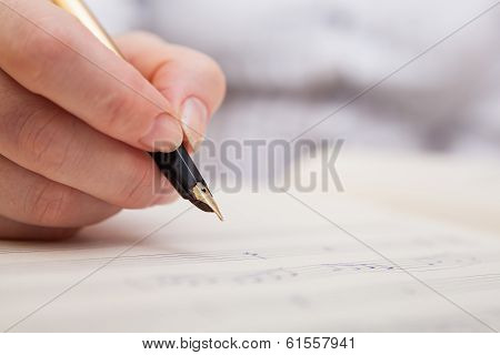Hand with pen and music sheet
