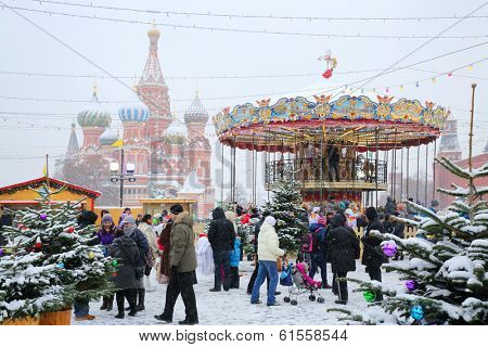 MOSCOW, RUSSIA - DEC 8, 2013: People walk near carousel and St. Basil cathedral during Christmas fair (area of fair is about 2 thousand square meters).